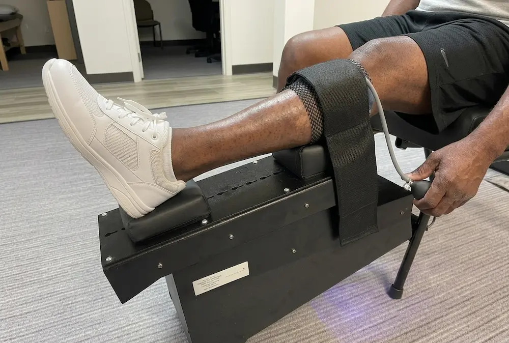 Black male sitting on knee decompression machine from m knee on trac