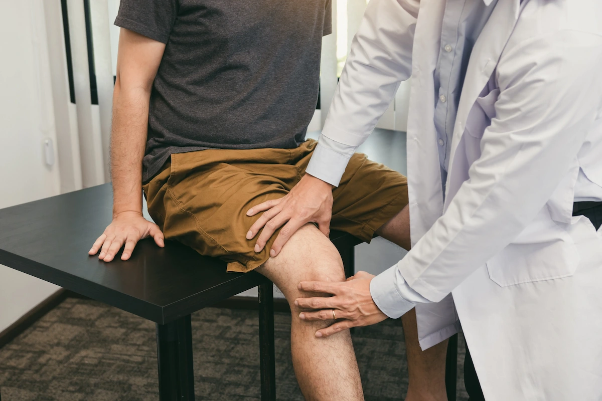 chiropractor inspecting patients knee while he sits on the table