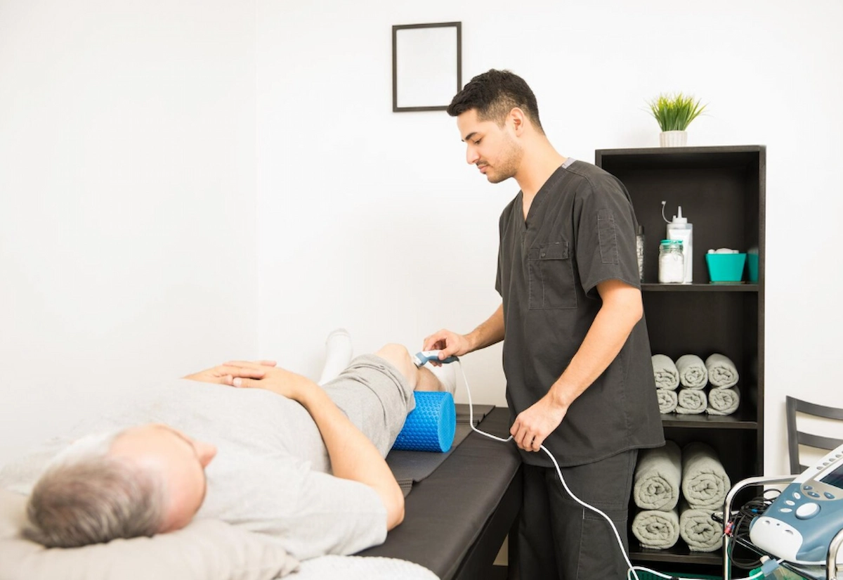 chiropractor administering shockwave therapy to a patients knee