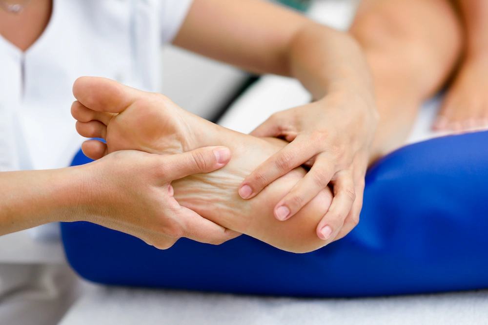 Person holding their foot due to numbness and tingling caused by peripheral neuropathy.