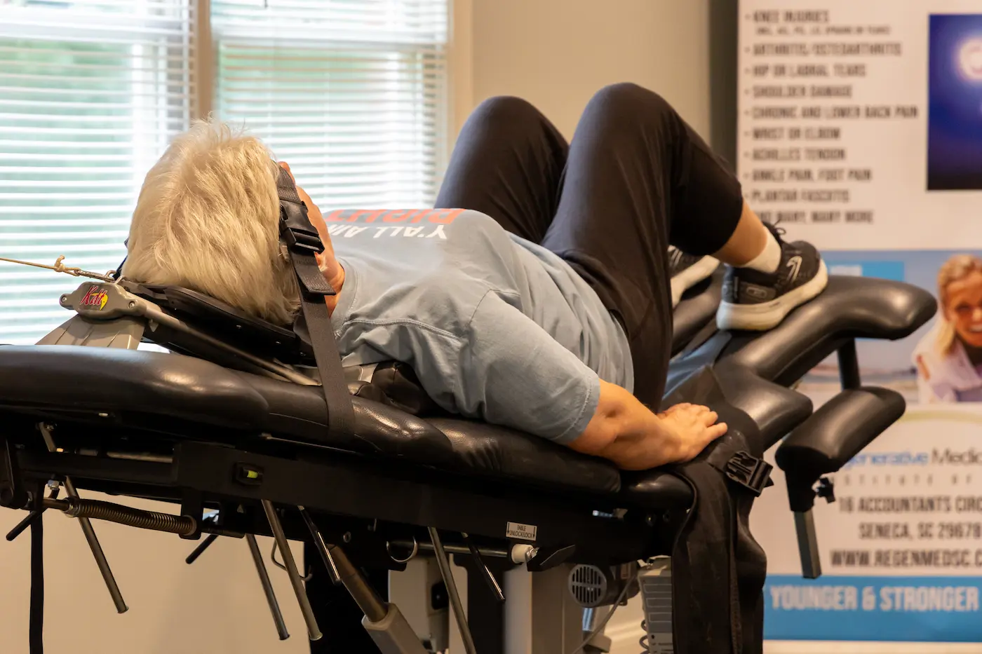 A person lies on a medical decompression table with their head secured by a harness, undergoing therapy.